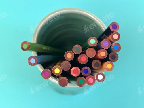Vorschau: Flaches Auflegen von Schreibtischutensilien, bunte Buntstifte in einer Tasse auf blauem Hintergrund