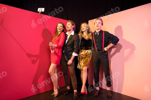 Preview: happy glamorous friends taking selfie on smartphone in studio