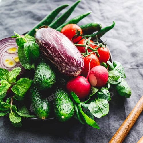 Preview: Various fresh colorful vegetables in a plate on a table with wooden kitchen utensils
