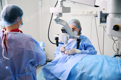 Preview: Female surgeon performs a surgical operation using a surgical microscope