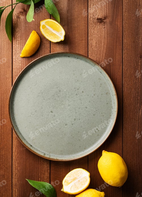 Preview: Fresh lemons around an empty green plate on a wooden background. Mock up. Citrus fruits for lemonade