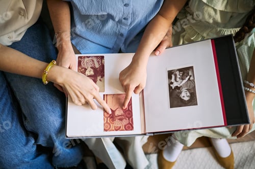 Preview: Family Members Reviewing Photo Album and Sharing Memories at Home