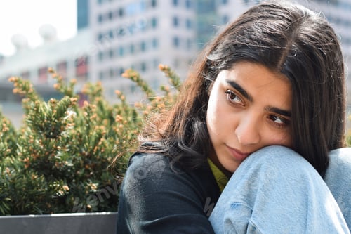 Preview: Young teenage girl sitting on city street bench feeling down sad upset lonely