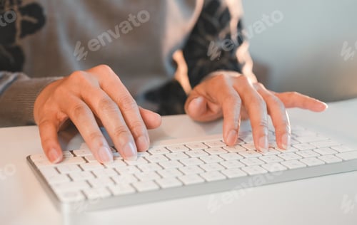 Preview: Hands typing on white wireless keyboard in modern workspace.Person fingers typing