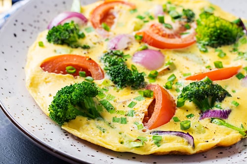 Preview: Omelette with broccoli, tomatoes and red onions on dark table. Italian frittata with vegetables.