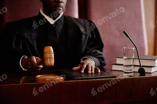 Preview: Focus on wooden gavel in hand of experienced male judge announcing verdict
