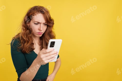 Preview: Worried redheaded woman using a mobile phone