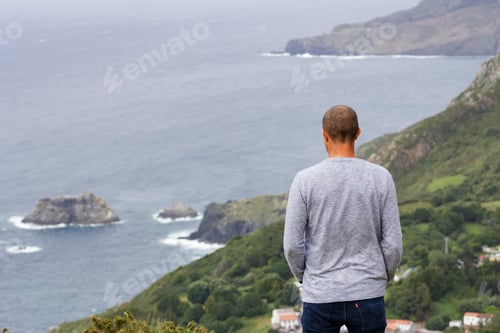 Preview: Man from behind standing on the top of cliffs in the coastline looking the sea, rocks, galicia