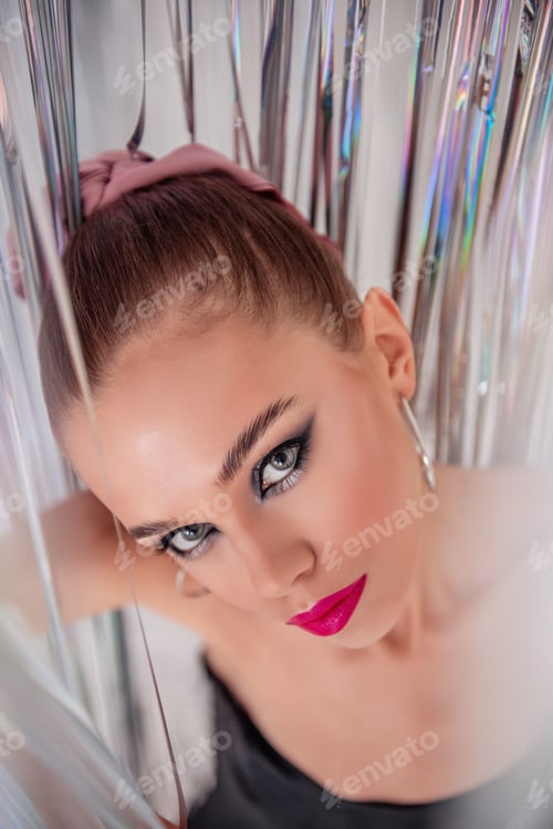 Preview: Top view of close-up portrait of fashion girl with bright pink lips, makeup in shiny foil tinsel
