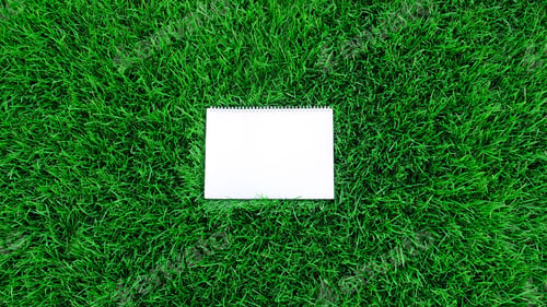 Preview: Mock-up empty white paper on green grass background. Сard on nature for message flat lay, copy space