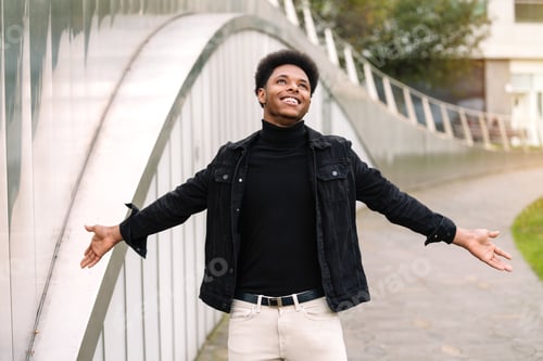 Preview: Moroccan man with afro hair with his arms open looking up very smiling and happy