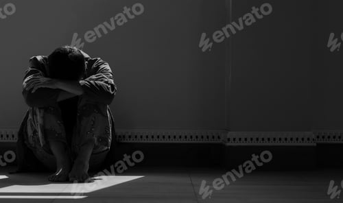 Preview: light and shadow on lonely hopeless man hugging knee on the floor in dark room