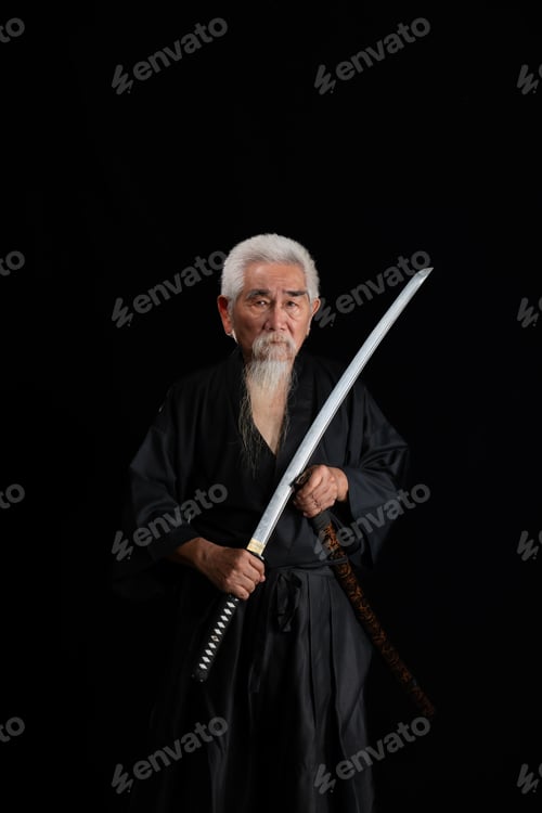 Preview: Senior Japanese samurai with katana sword on black background, studio shot