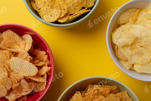 Preview: Overhead close-up of various snacks in bowls on yellow background