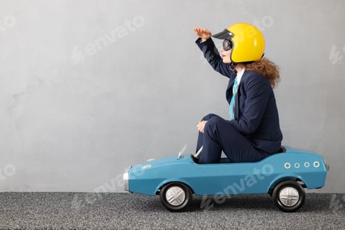 Preview: Successfull businesswoman driving toy car outdoor