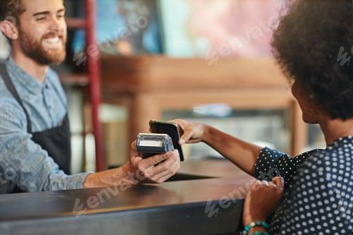 Preview: Shot of a barista taking a smartphone payment from a customer at a cafe