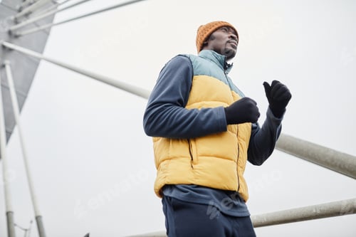 Preview: Young black man in sportswear and gloves running in urban environment