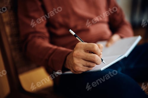 Preview: Close up of man taking notes at home.