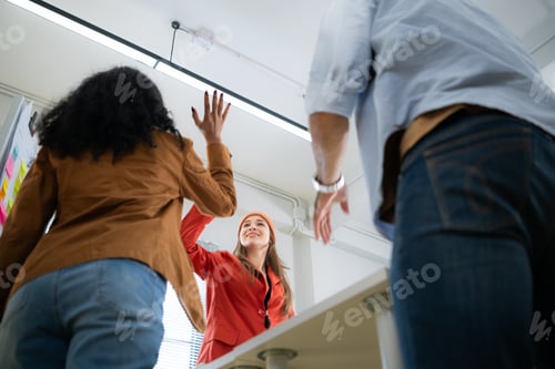 Preview: Low angle view of businesswoman giving high five to colleague in office