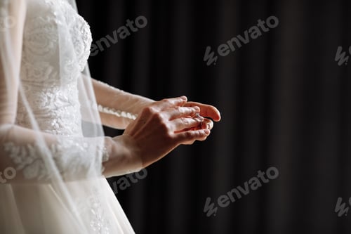 Preview: cropped photo of gentle hands of the bride standing in a white lace dress puts a wedding ring