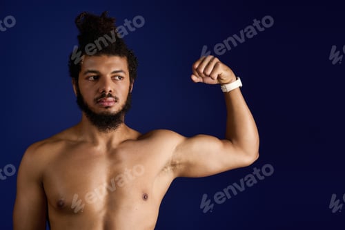Preview: Athletic African American man exercising with strength on a blue background