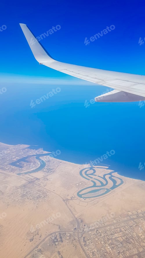 Preview: View from the window of plane on blue sky and earth with landscape of desert, sea and canals in
