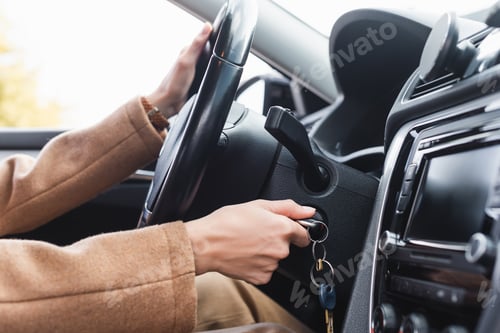 Preview: partial view of woman starting car while holding steering wheel