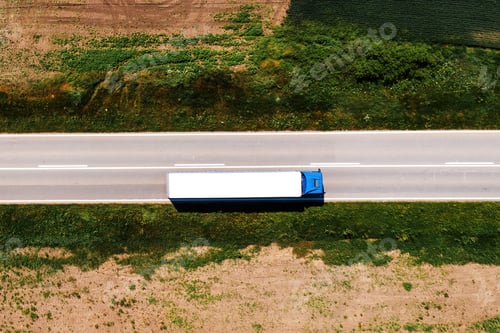Preview: Aerial shot of semi-truck driving along the highway through countryside landscape, drone pov