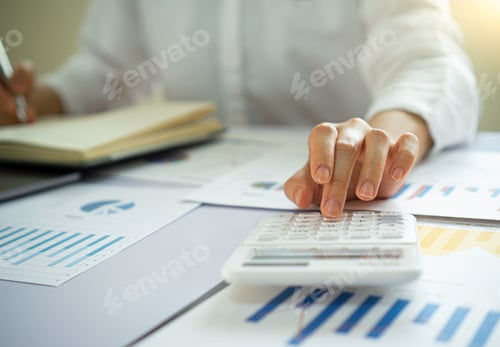 Preview: The female finance staff is calculating the company's profits from the graph on the home office desk