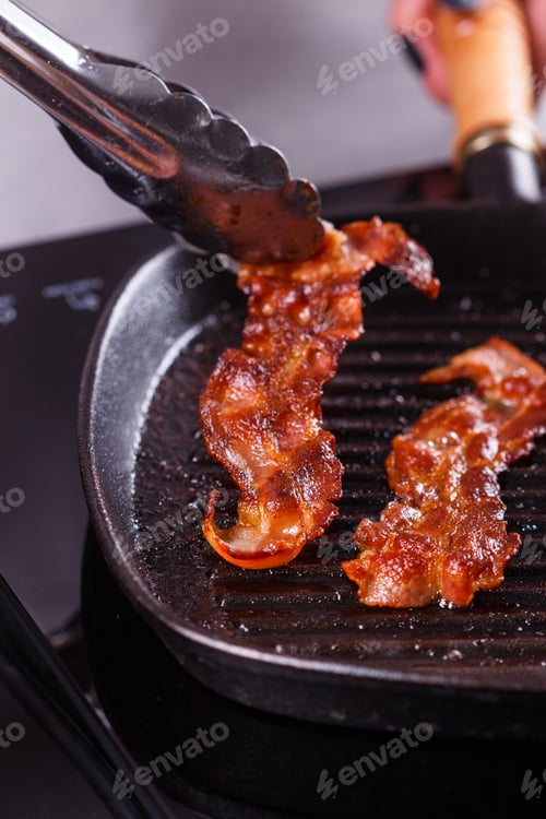 Preview: young woman in a gray apron fries bacon
