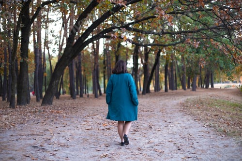 Preview: Sad lonely woman in a blue dress walking in the autumn park. Back view.