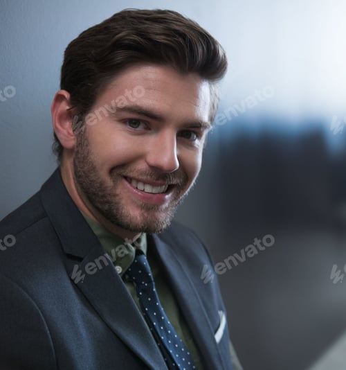 Preview: Male business professional smiling at camera in office, wearing olive-green shirt and polka-dot tie