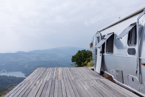 Preview: A modern camper trailer is parked on a wooden deck overlooking