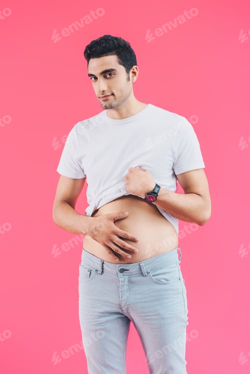 Preview: cheerful handsome man palming belly and looking at camera isolated on pink