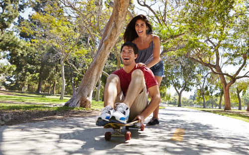 Preview: Young couple skateboarding in park