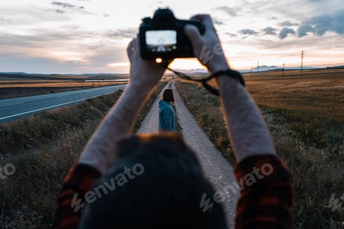 Visualização: Homem com câmera atirando em mulher perto da estrada entre campos