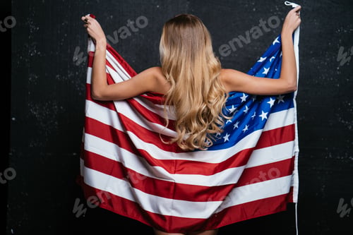 Preview: Beautiful blonde woman wrapped in the flag of the united states of america smiling