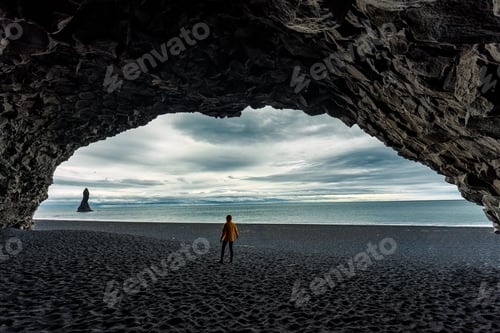 Preview: Reynisdrangar natural rock formation with female tourist standing in halsanefshellir cave