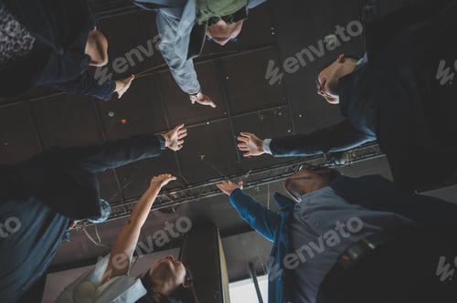 Preview: large business team showing unity with their hands together, business team celebrating