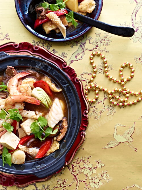 Preview: A bowl of seafood soup on an ornate table setting.