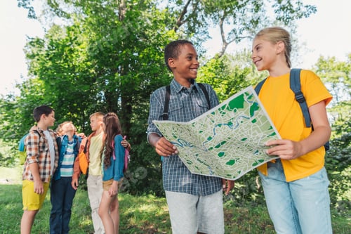 Preview: selective focus of african american boy smiling with friend while holding map