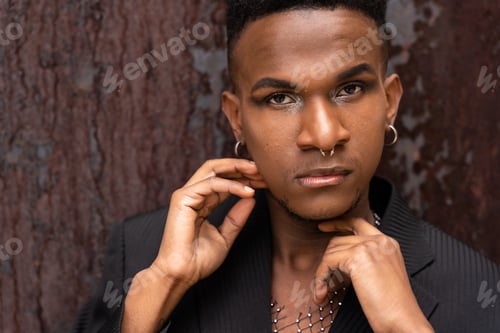 Preview: A male model of black ethnicity in a fashion pose on a brown metallic background