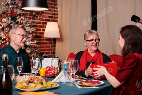 Preview: Family exchanging christmas gifts at festive table