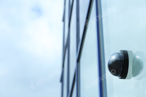 Preview: Modern CCTV security camera on building wall outdoors. Space for text