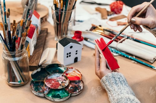 Preview: Close-up image of woman crafting and painting wooden ornaments and decorations.