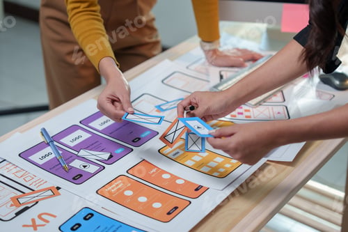 Preview: Web designers collaborating on developing a mobile application, arranging various options for the us