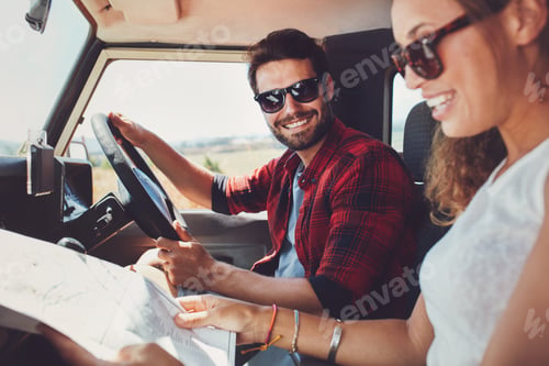 Preview: Young couple sitting inside their car with map