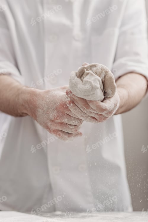 Preview: Professional baker kneads dough in his hands in the kitchen of the bakery