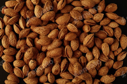 Preview: Top view of handful of pecans, almonds on a black background. Closeup. Micro.
