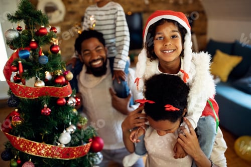 Visualização: Garota negra feliz se divertindo com sua família no dia de Natal em casa.